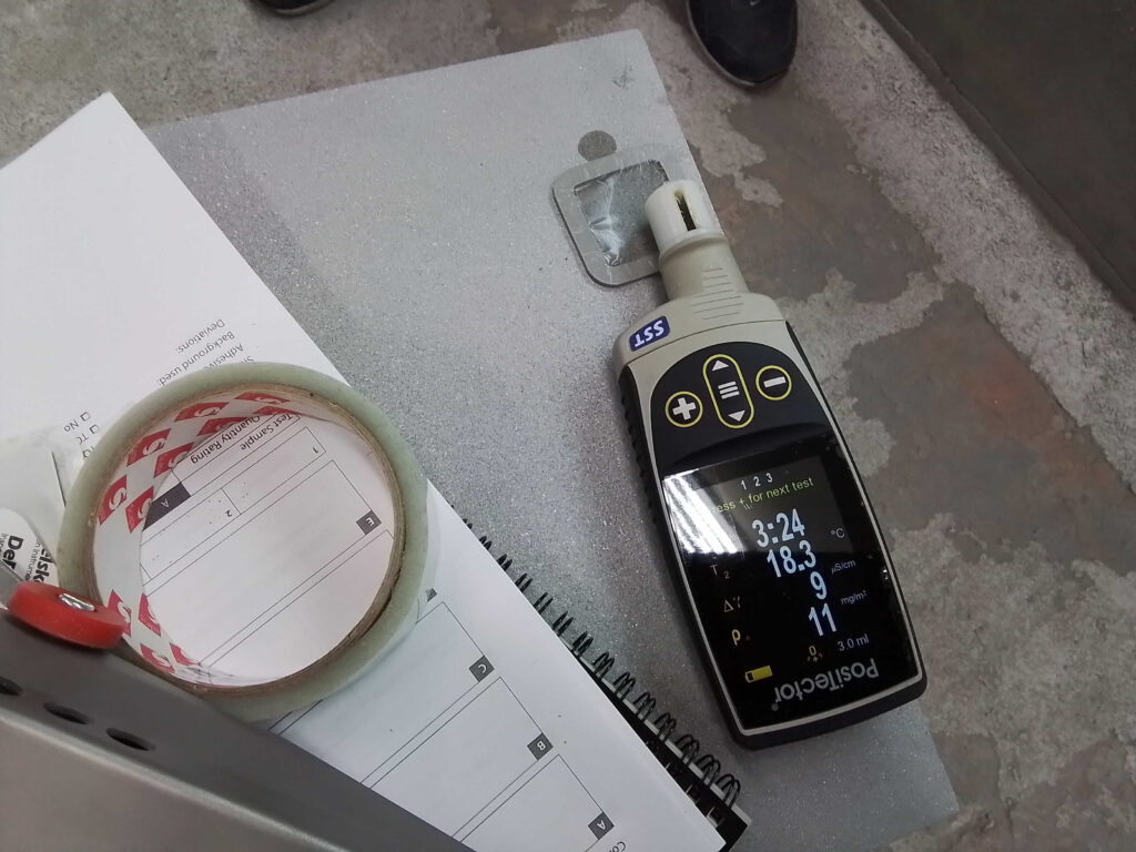 Inspector applying the Detail Effect by measuring coating thickness with an Elcometer device during quality control on an industrial structure.